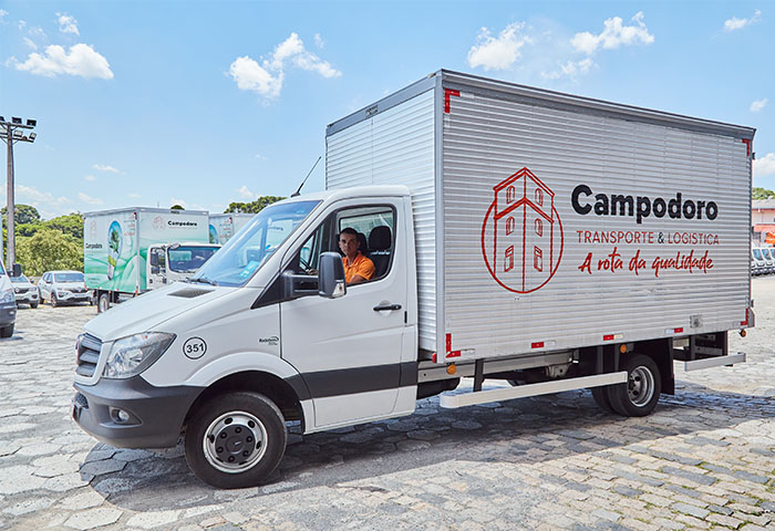 Motorista da Campodoro dentro de caminhão identificado com a marca, pronto para iniciar a rota de entrega.