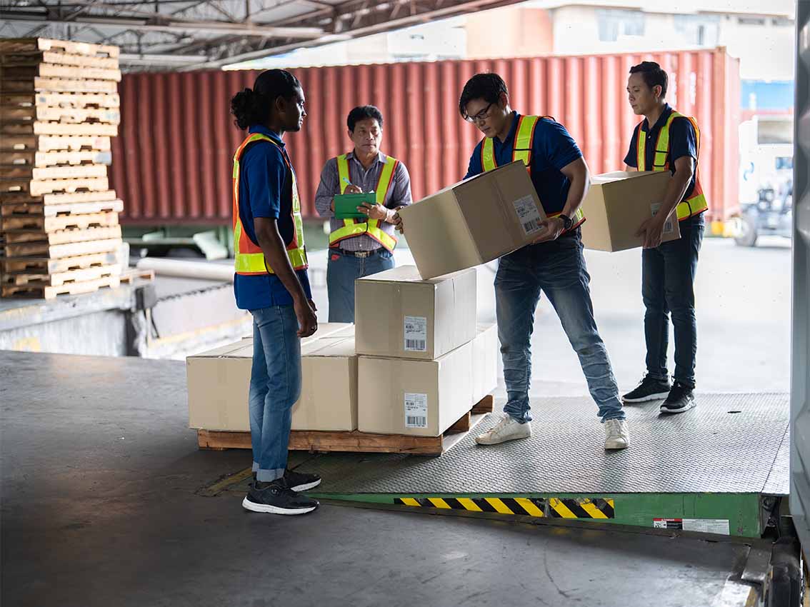 Equipe de logística carregando caixas em uma plataforma de carga em armazém.
